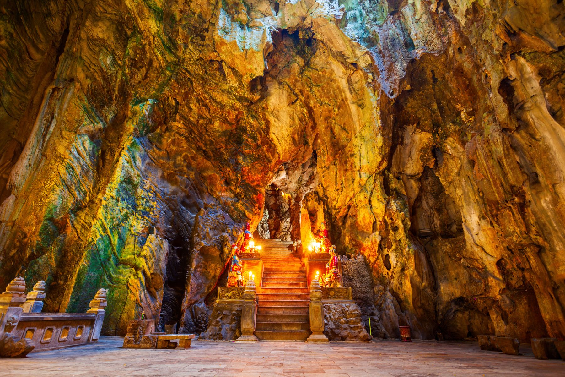 Inside Huyen Khong Cave at Marble Mountains, with sunlight streaming through the ceiling onto Buddhist carvings