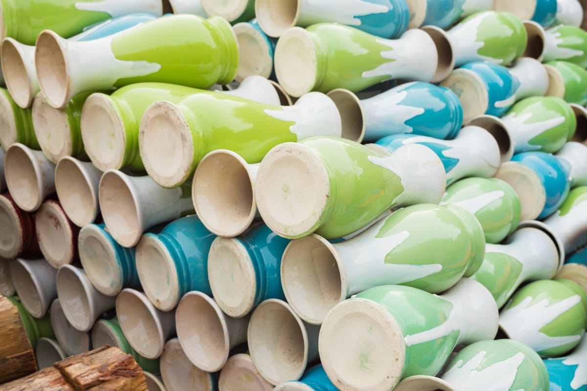 Rows of white pottery with green and blue designs stacked at Bat Trang Pottery Village, showcasing traditional Vietnamese ceramic craftsmanship