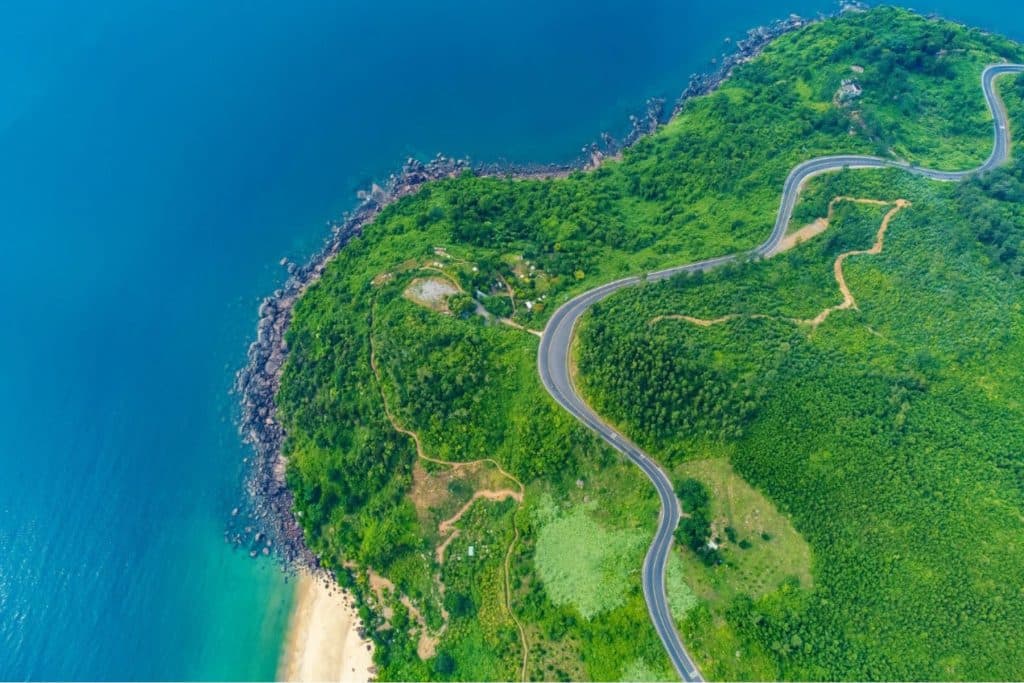 Scenic view of Hai Van Pass with lush forests, winding roads, and the ocean in the distance, featured in the Hai Van Pass Scenic & Cultural Photo Tour