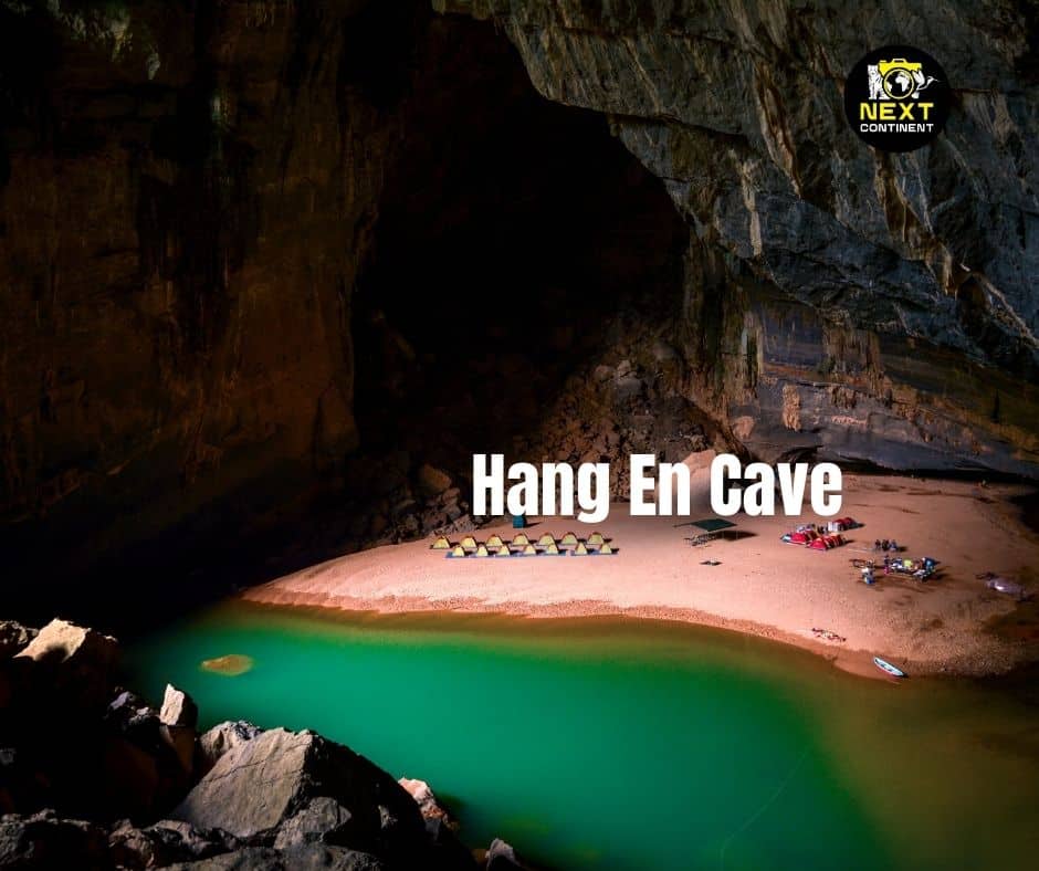 Tents set up along a sandbar inside Hang En Cave with greenish waters in the cave’s center