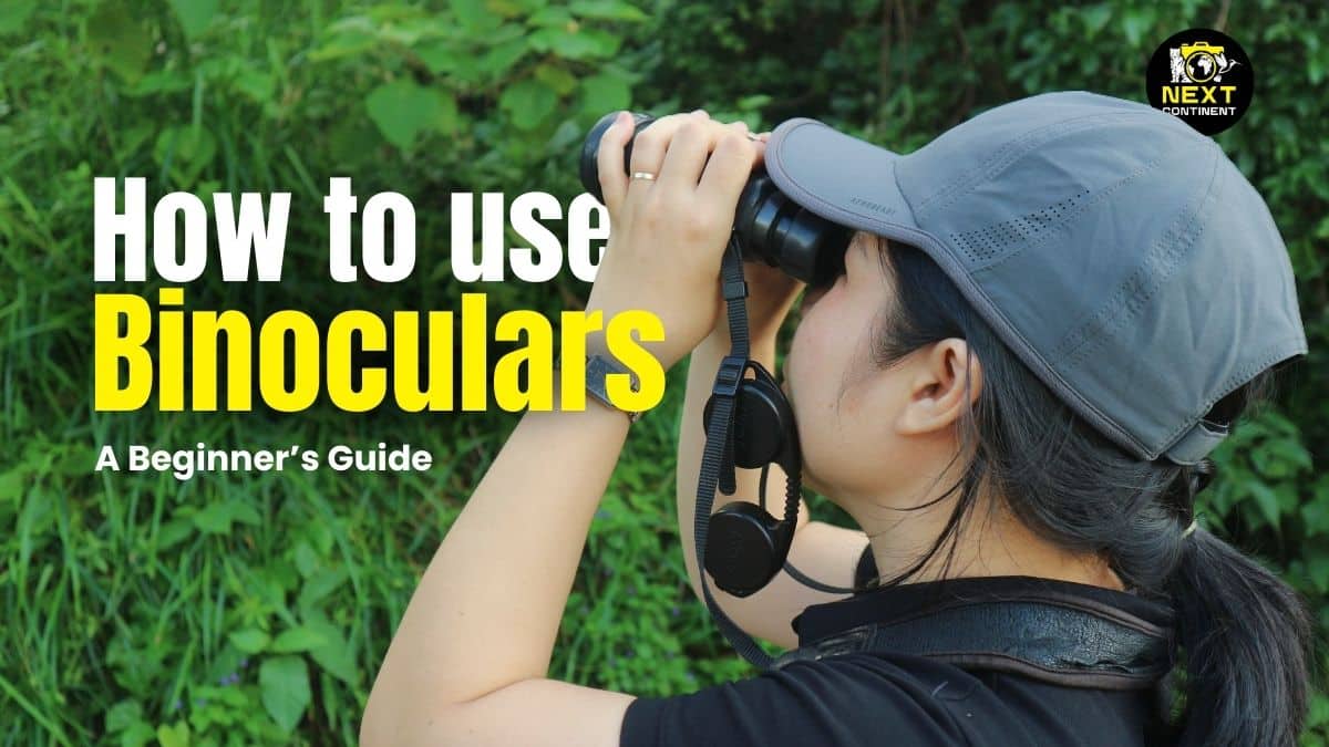 A woman looking through binoculars while standing on a mountain, featured in the blog 'How to Use Binoculars: A Beginner’s Guide
