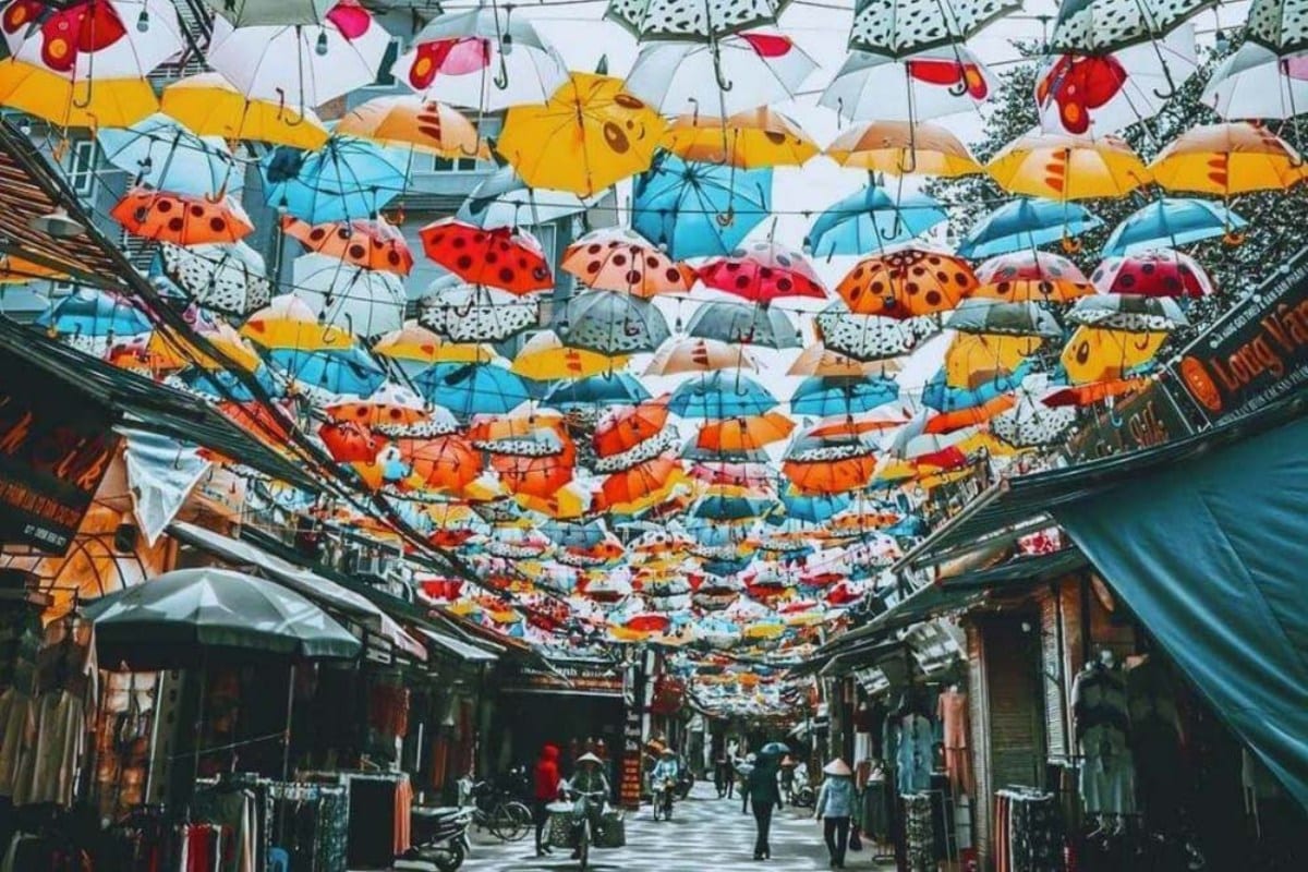 Vibrant colored umbrellas hanging over a bustling street at Van Phuc Silk Village, Hanoi, creating a lively atmosphere in Vietnam's oldest silk-weaving hub