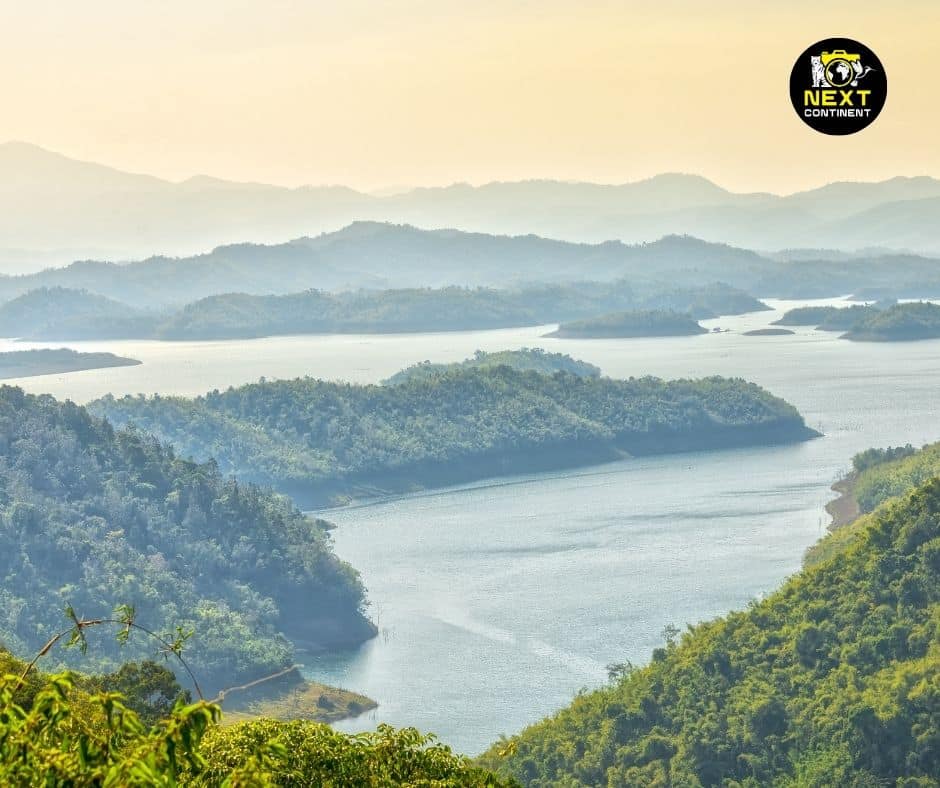 A breathtaking view of Ta Dung Lake in Đắk Nông province, Vietnam, showcasing its vibrant blue waters surrounded by lush green mountain islands under a clear sky.